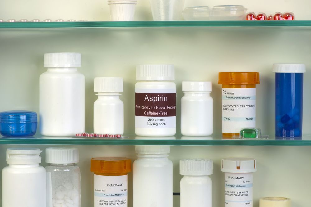 Armoire à pharmacie avec un flacon d'aspirine, soulignant la nécessité de stocker les médicaments en toute sécurité, hors de portée des animaux de compagnie, y compris des chats, pour éviter toute ingestion accidentelle et tout dommage potentiel.