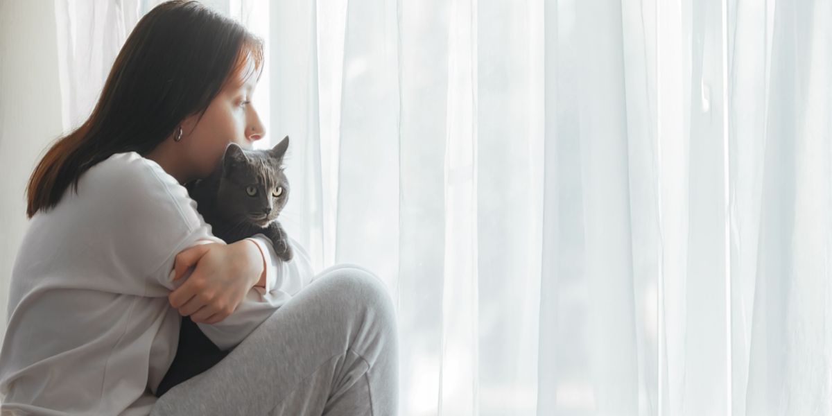 Image d'une femme triste assise avec un chat, indiquant peut-être un moment de réconfort ou de soutien.