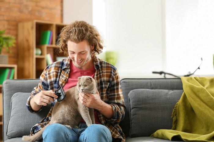 Image représentant une personne toilettant doucement un chat, illustrant le soin et l'attention apportés au maintien du bien-être et de l'apparence du chat.