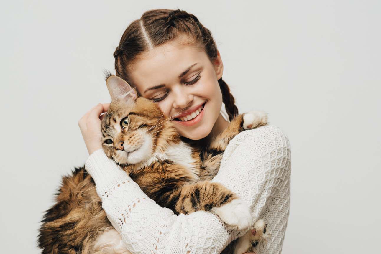 Image montrant un chat patient amoureusement embrassé par son propriétaire, soulignant un moment tendre de connexion et d'affection entre l'homme et l'animal.