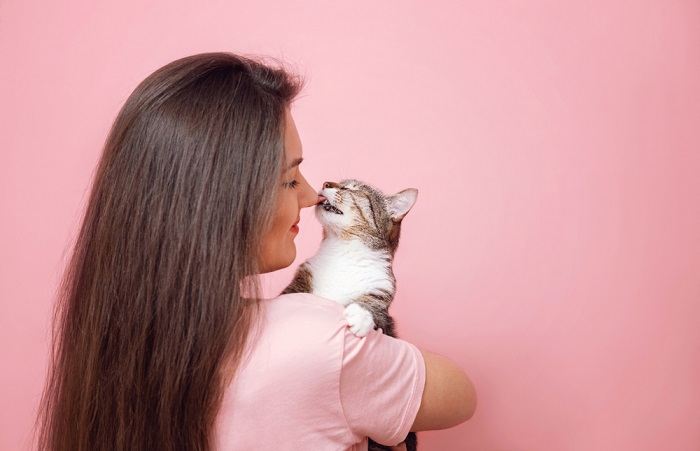 Photo d'un chat léchant doucement la main d'une fille, illustrant une interaction douce et nourrissante entre le chat et l'enfant.