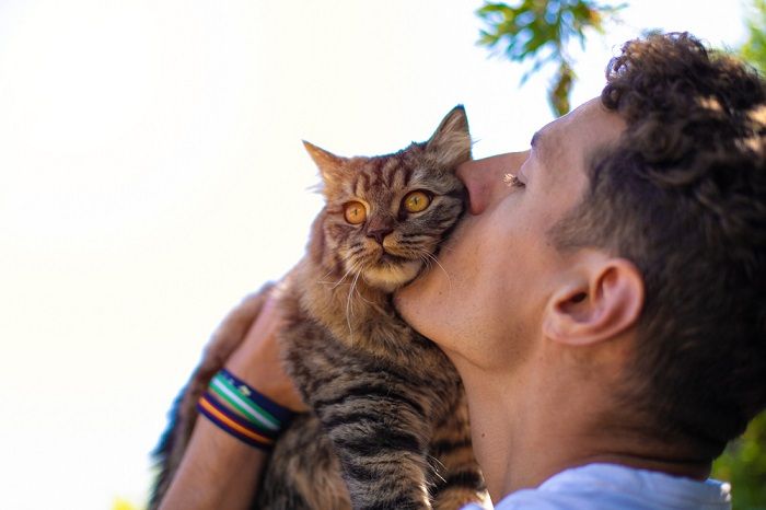 homme dans le jardin serrant et embrassant un chat