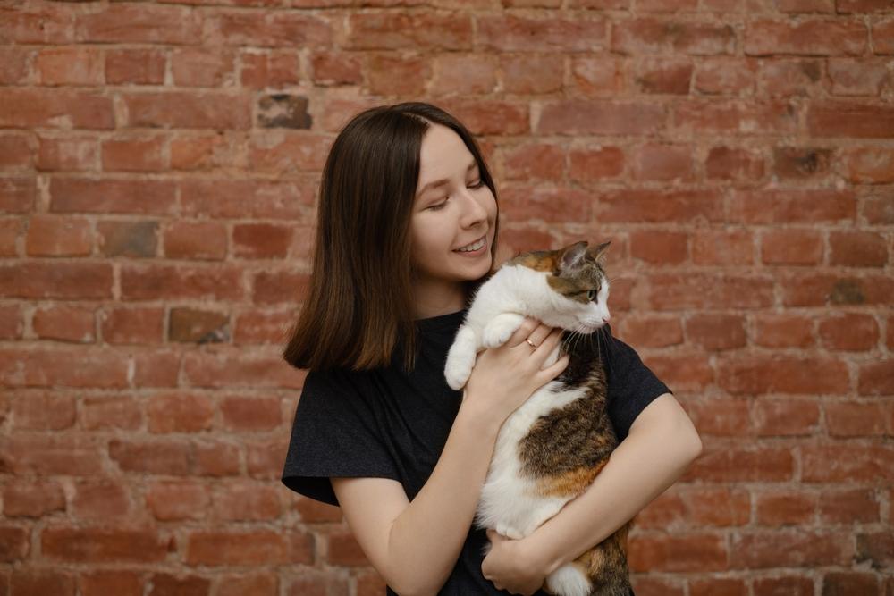 une femme tient un chat et regarde ailleurs