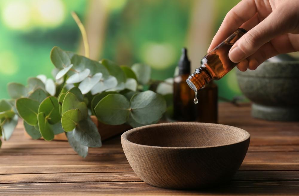 Une image capturant une femme versant délicatement de l'huile essentielle d'eucalyptus