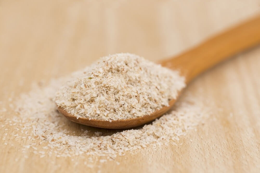 Cuillère en bois avec graines de psyllium sur fond en bois